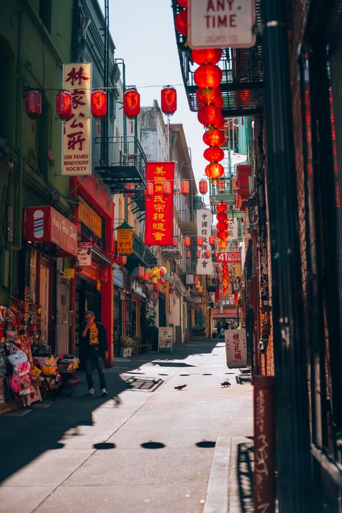 Free Sunlit street in Chinatown with red lanterns and traditional signage. Stock Photo