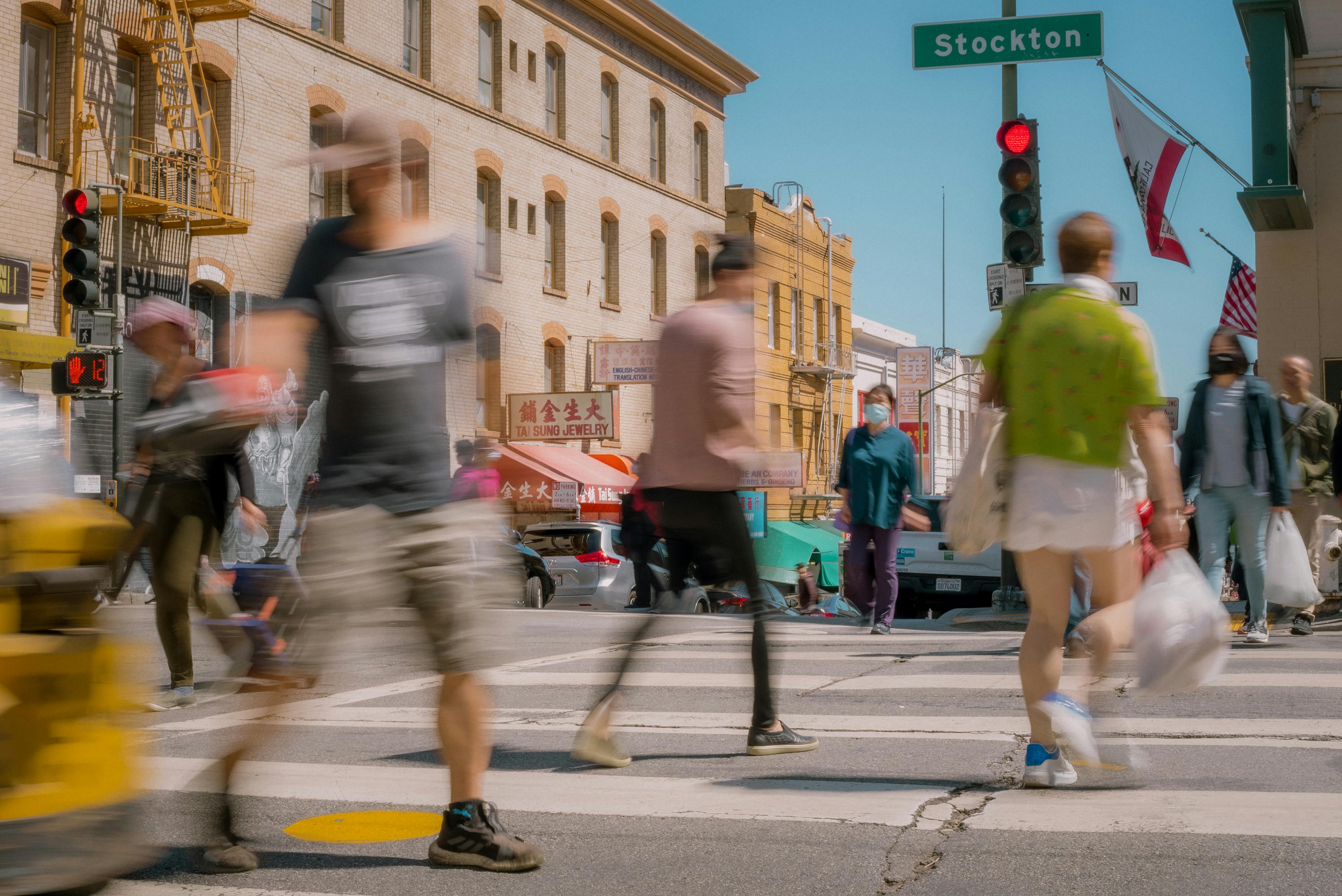 Motion blur of pedestrians in a vibrant city intersection, colorful urban scene.
