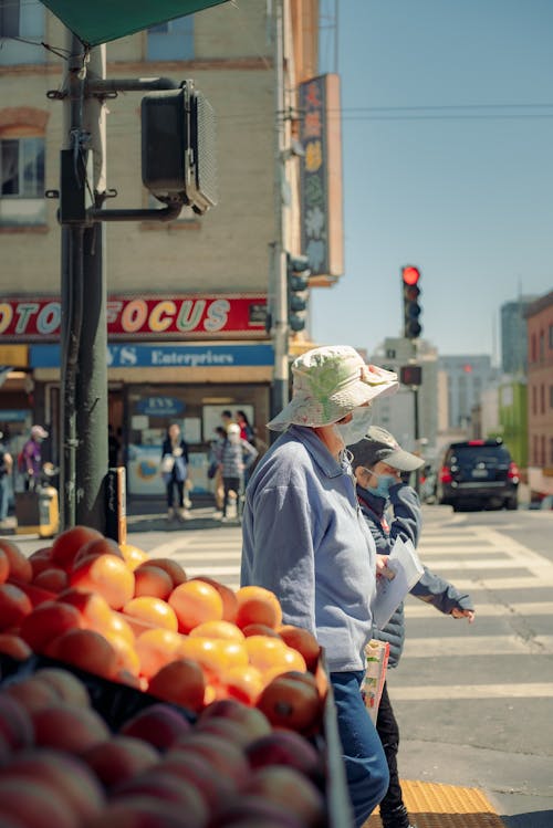 Person with Face Mask Walking Next to Stall on Street