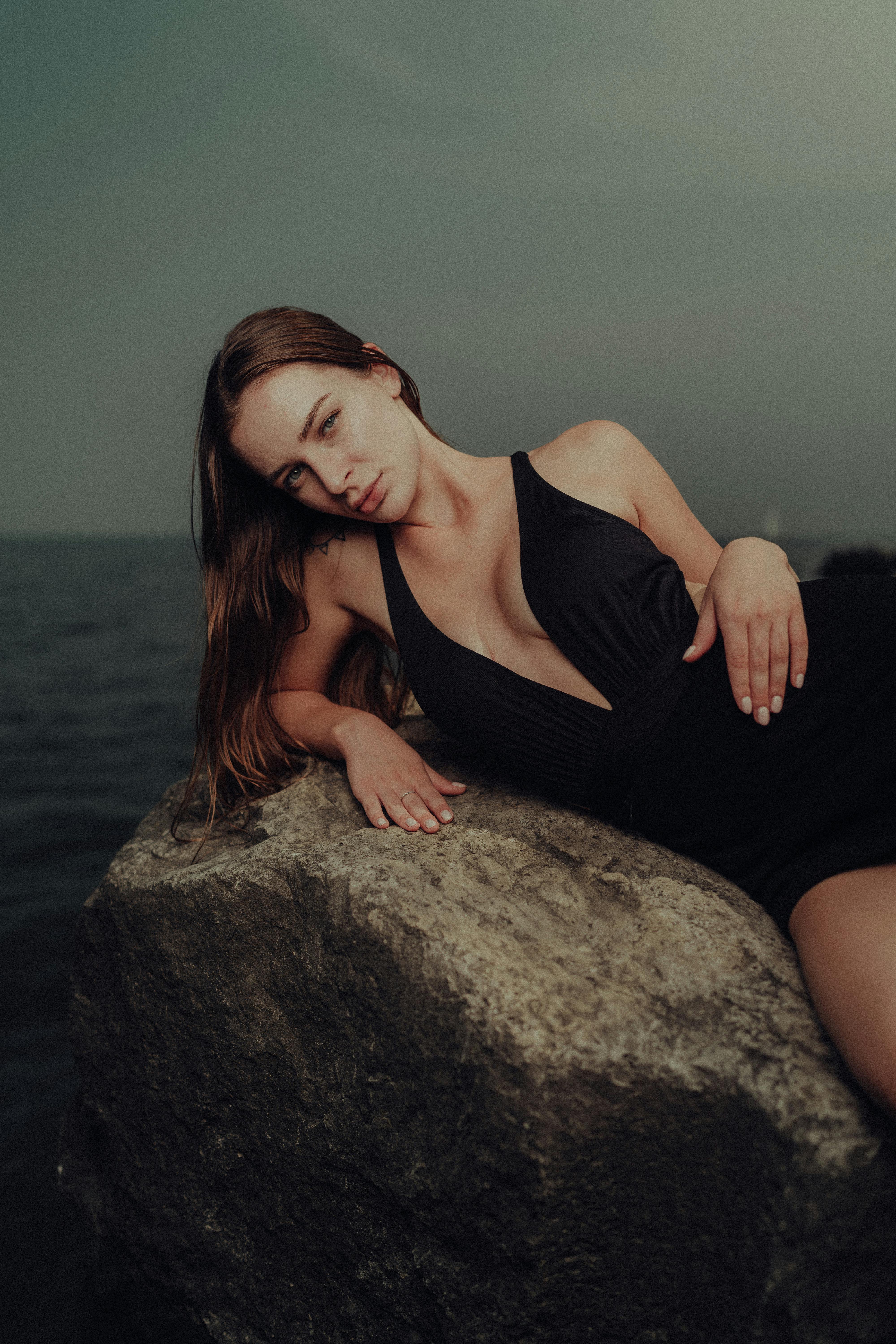 a woman laying on a rock in black swimsuit