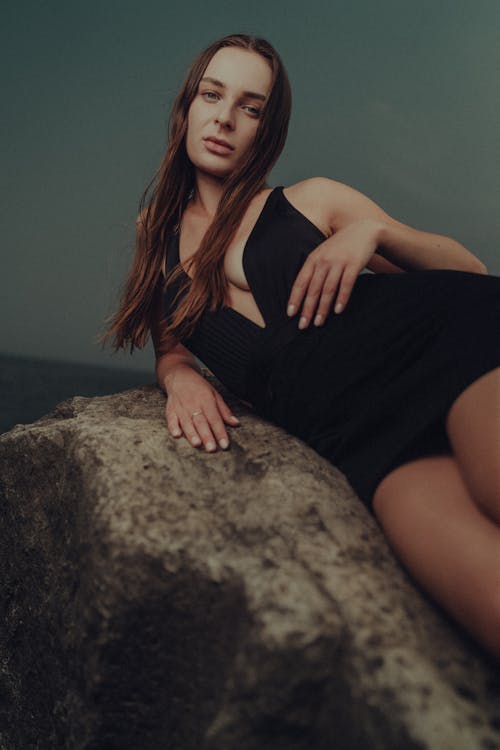 A woman in a black dress sitting on a rock