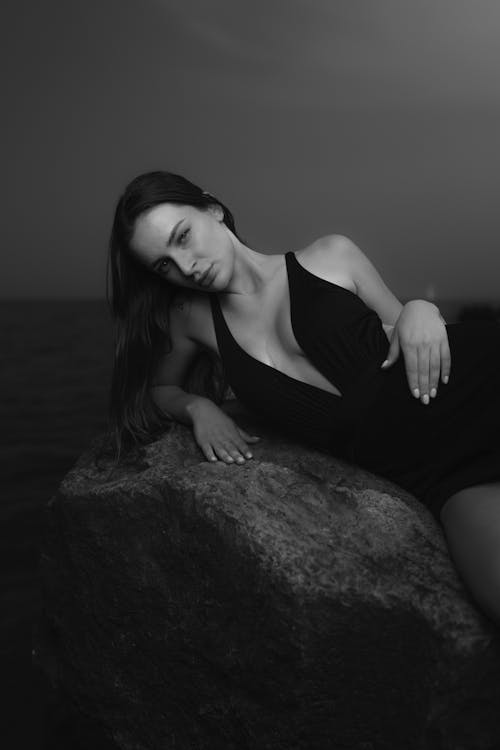 A woman in black and white sitting on a rock