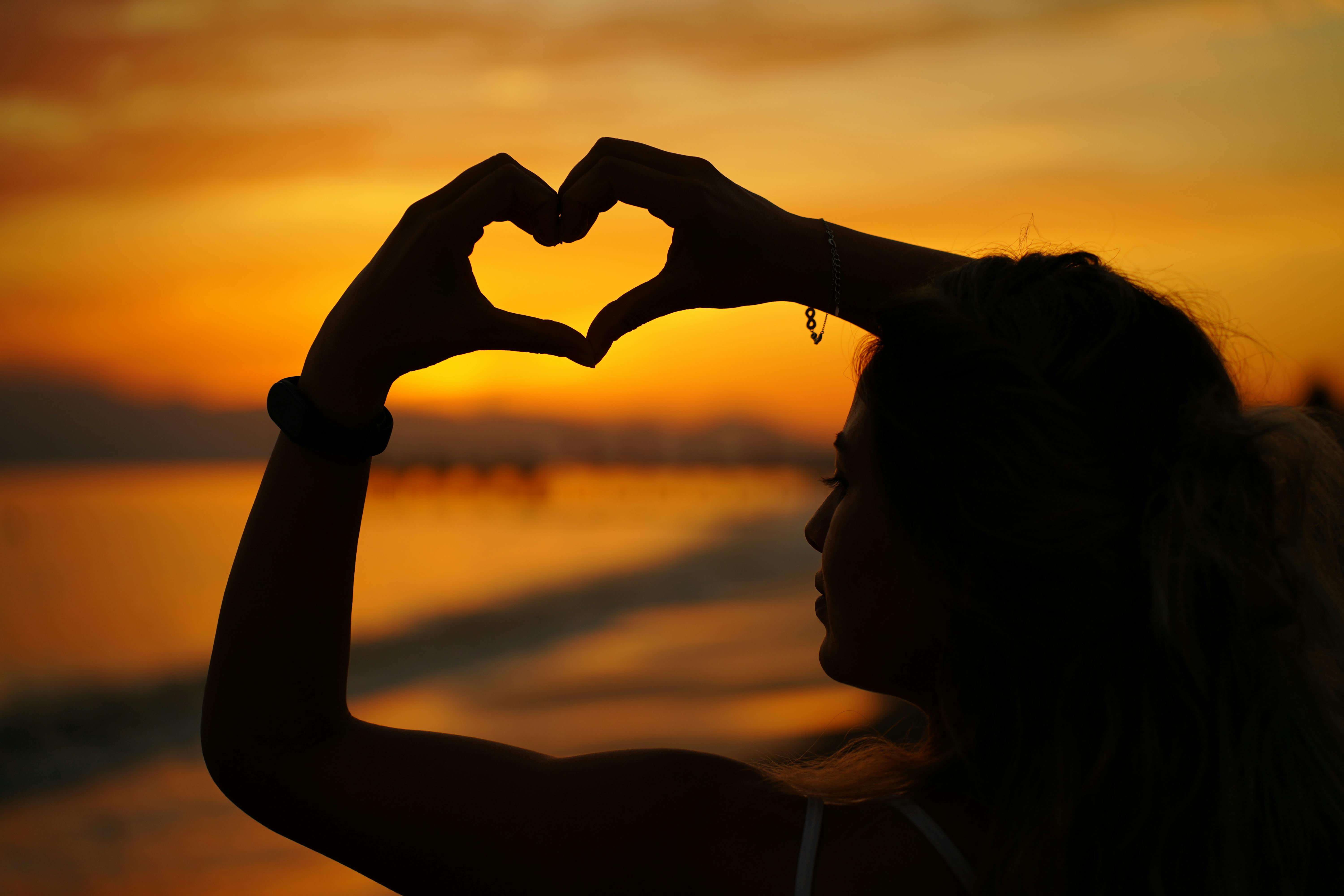 Silhouette of Woman Making Heart Shape at Sunset · Free Stock Photo