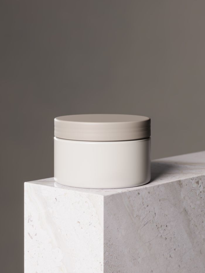 Unlabelled white cosmetic jar with a grey lid on marble — photo by Carlos Diaz on Pexels