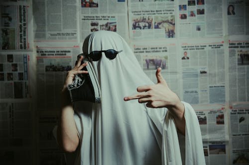Person Dressed as Ghost Posing with Sneaker in Hand