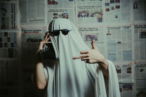 Free Person dressed as a ghost showing humor and attitude in front of newspaper backdrop. Stock Photo