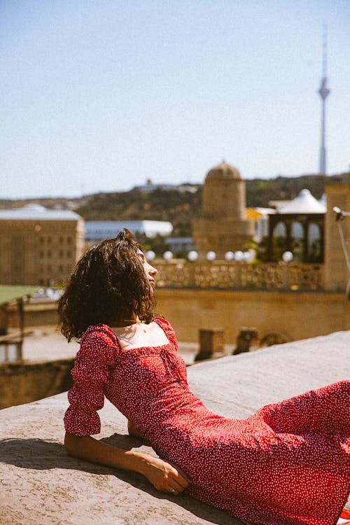 Woman in a Dress Lying on a Surface with the View of the Old Town