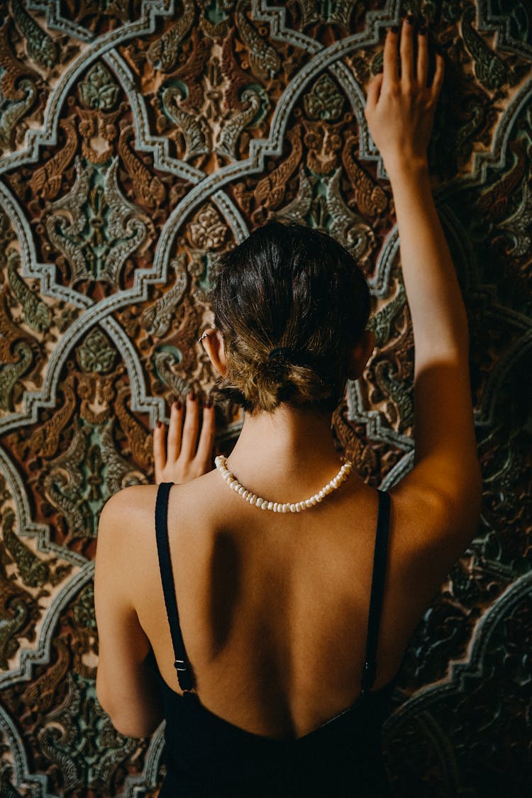 Back View Of An Elegant Woman On The Background Of A Wall With An Artistic Pattern