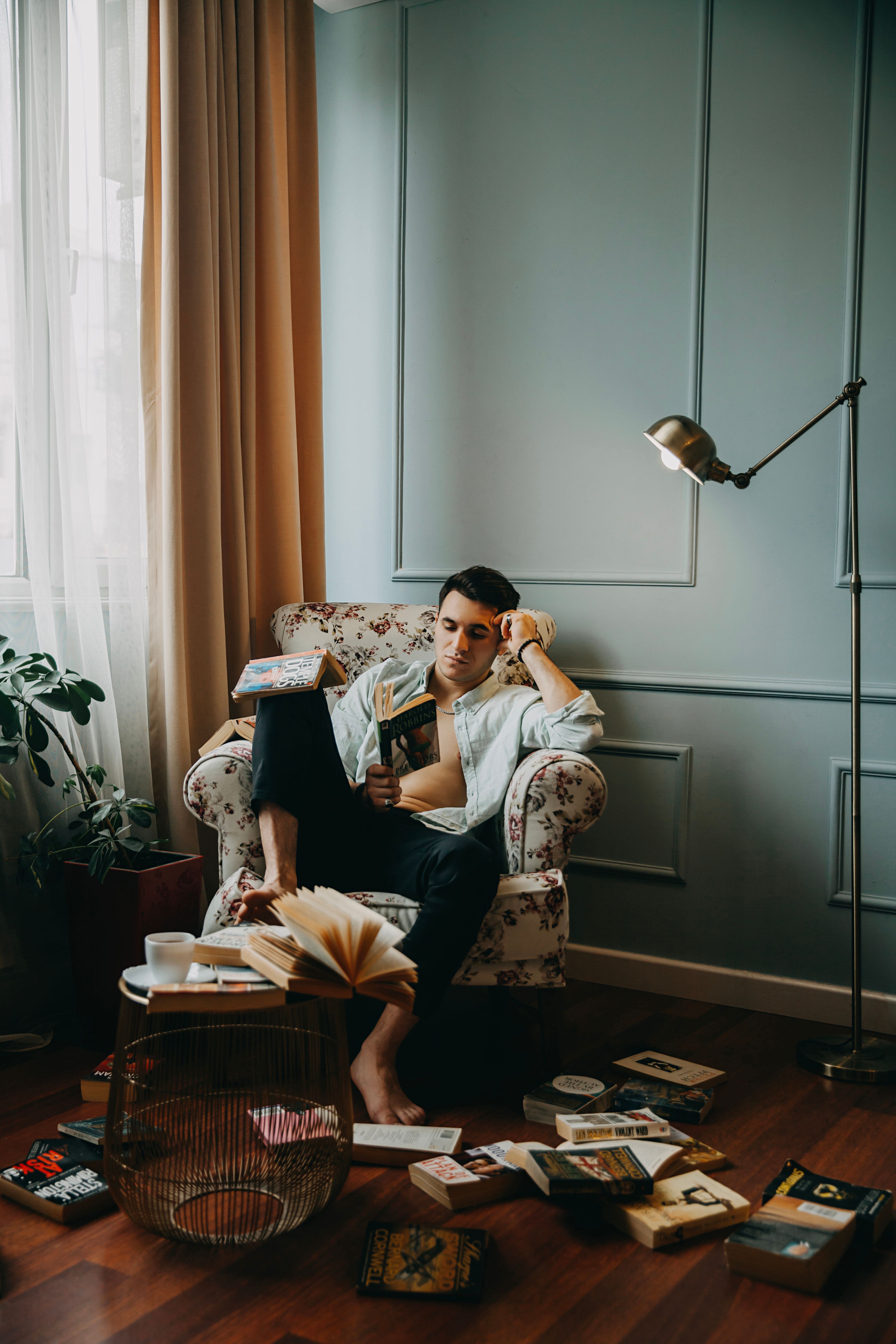 A man reading in a cozy corner surrounded by scattered books