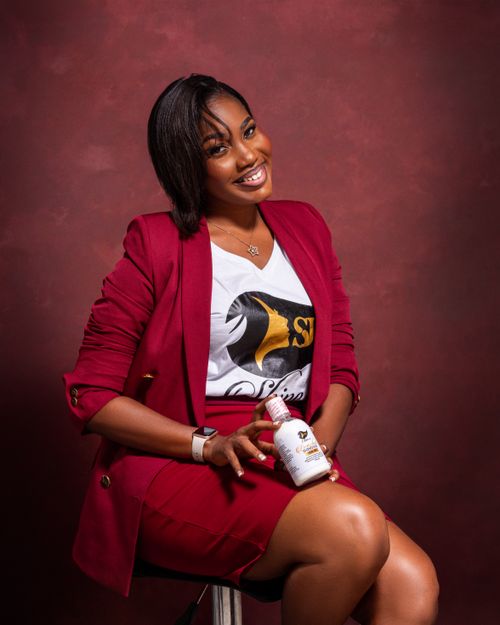 Free Stylish young woman in a red blazer and skirt, confidently posing and smiling while holding a product. Stock Photo