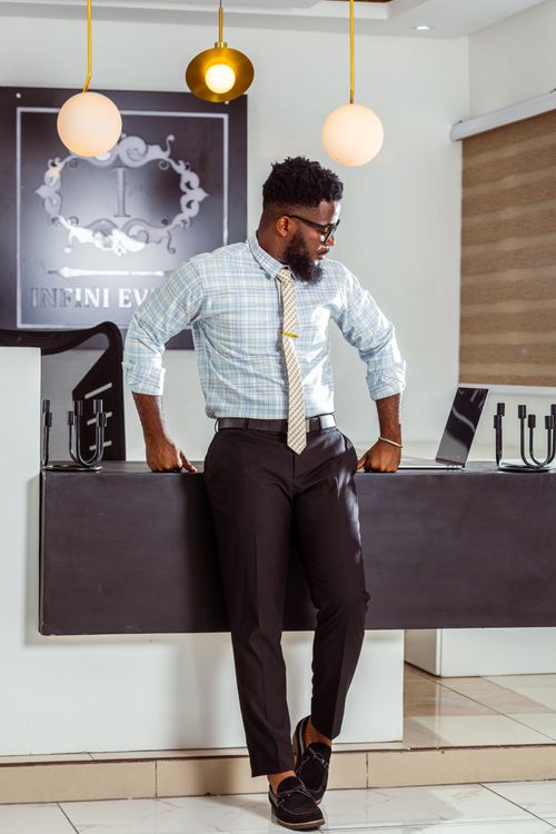 Free Businessman in stylish attire leaning on a reception desk in a contemporary office. Stock Photo