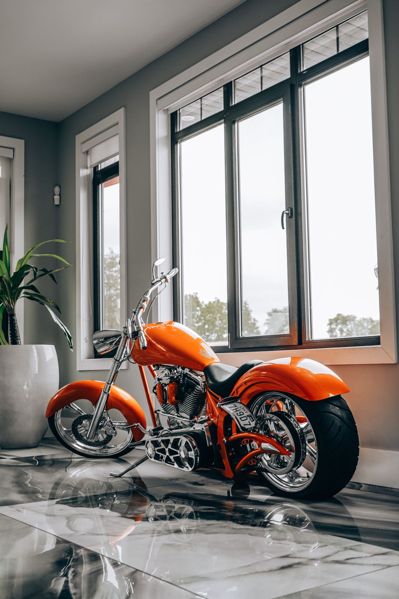 A sleek orange motorcycle displayed indoors by large windows