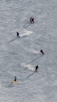 A group of skiers enjoy a thrilling descent on a snowy mountain slope under the sun.