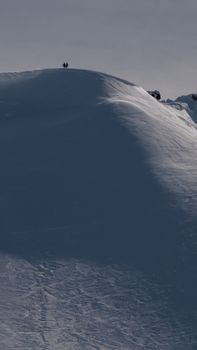 Skiers at the pinnacle of a snowy mountain under a clear, sunny sky. Perfect for winter sports enthusiasts.