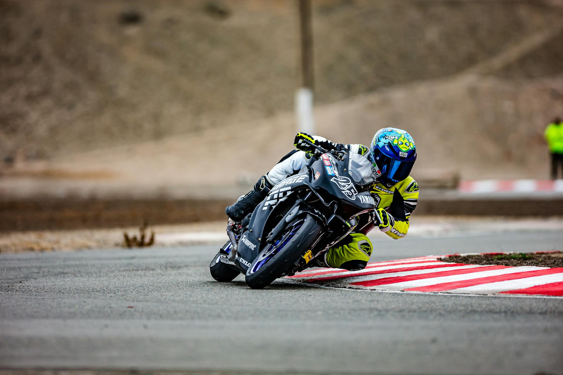 Motorcyclist leaning during a high-speed race on an outdoor track.