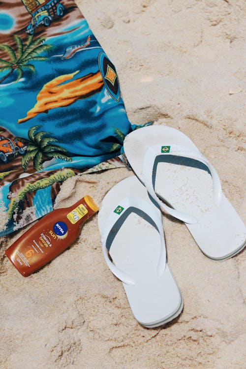 Free Flip-flops, Towel and a Sunscreen on the Beach  Stock Photo