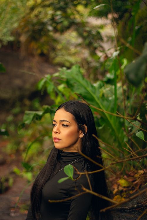 Free A serene portrait of a woman standing amidst lush greenery, capturing a tranquil outdoor moment. Stock Photo
