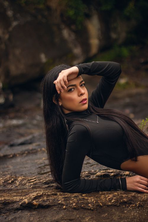 Free Elegant portrait of a young woman in a bodysuit posing naturally on a rock outdoors. Stock Photo