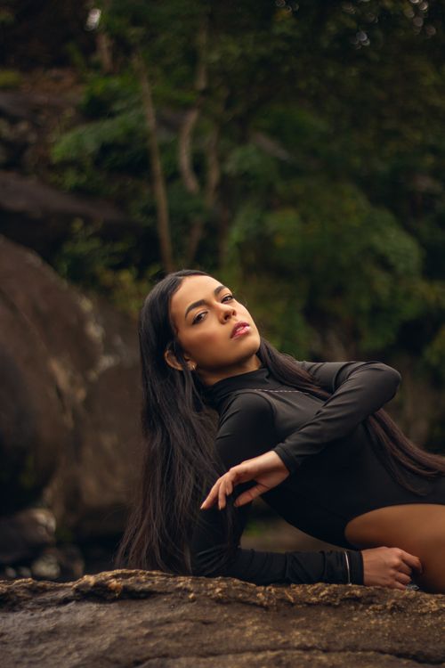 Free A young woman in a bodysuit gracefully poses against natural rock formations outdoors. Stock Photo