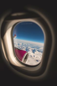 Scenic view through an airplane window displaying a vast sky and clouds during flight.