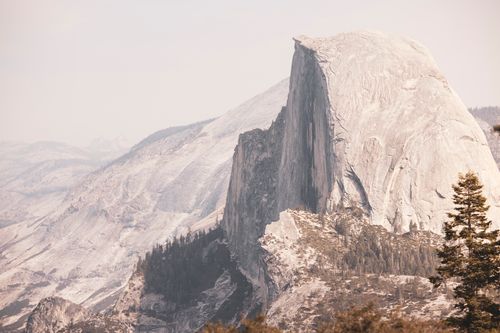 Free Scenic view of Half Dome in Yosemite National Park with rocky cliffs and conifer trees. Stock Photo