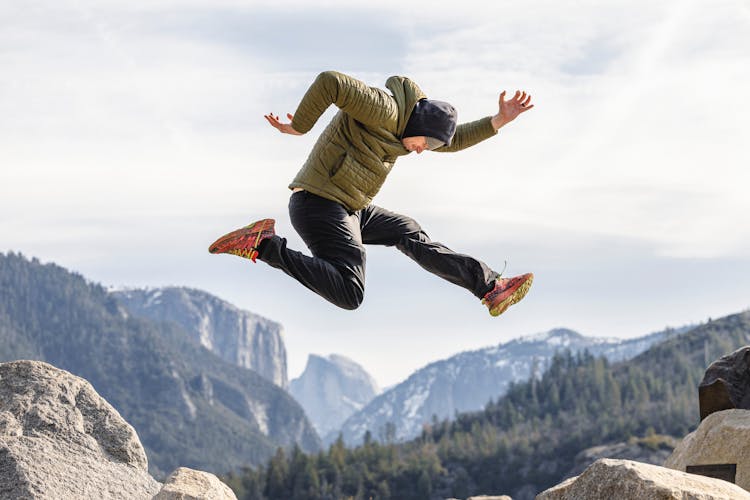 Man Jumping Over The Rocks In Mountains 