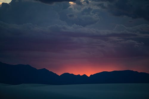 Silhouetted Mountains under a Cloudy Sunset Sky 