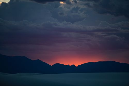 Free A stunning sunset with vibrant skies over silhouetted mountains and dramatic clouds. Stock Photo