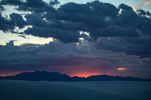 Free Vibrant sunset with dramatic clouds over a mountainous silhouette, creating a stunning natural scene. Stock Photo