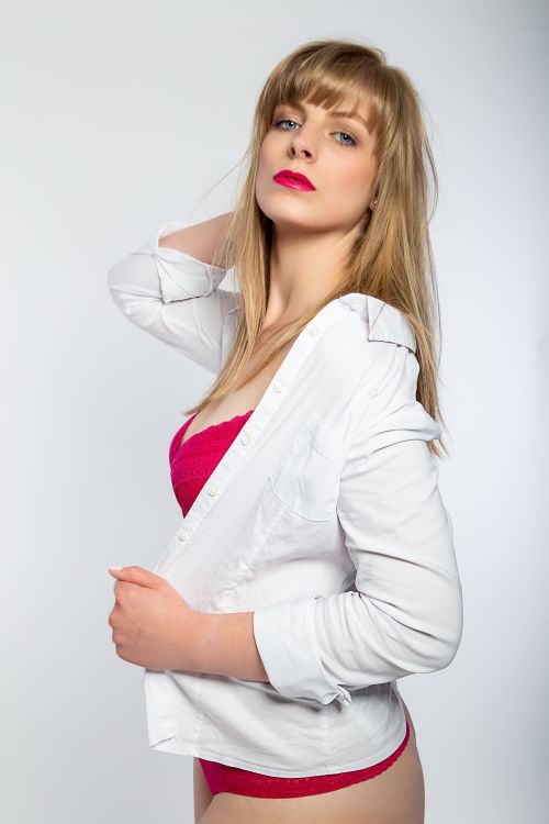 Free Stylish portrait of a blonde woman wearing a white shirt and pink underwear on a white background. Stock Photo