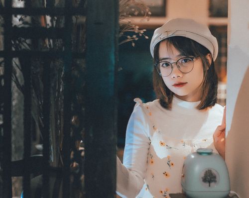 Free Elegant portrait of a woman wearing eyeglasses and a hat, with a warm and intimate indoor ambiance. Stock Photo