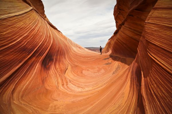 A person walking through layered sandstone formations. Photo by Stephen Leonardi on Pexels.