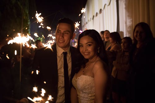 Bride and Groom Standing with Guests and Holding Sparklers