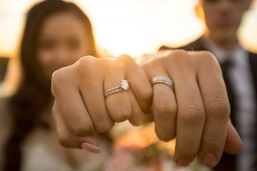 Novios mostrando anillos al atardecer