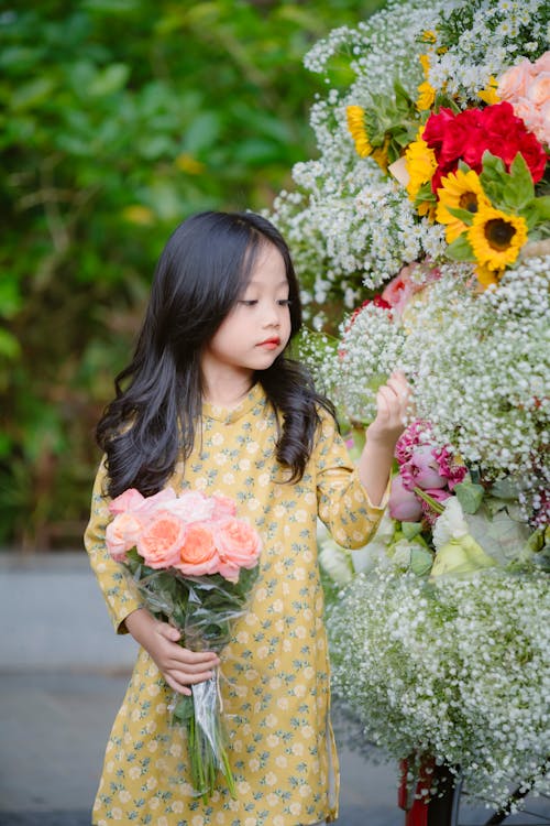 A Little Girl Standing next to a Flower Arrangement
