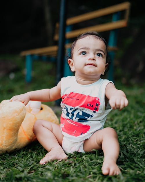 Free Little Toddler Boy Sitting on Grass with a Plush Toy Stock Photo