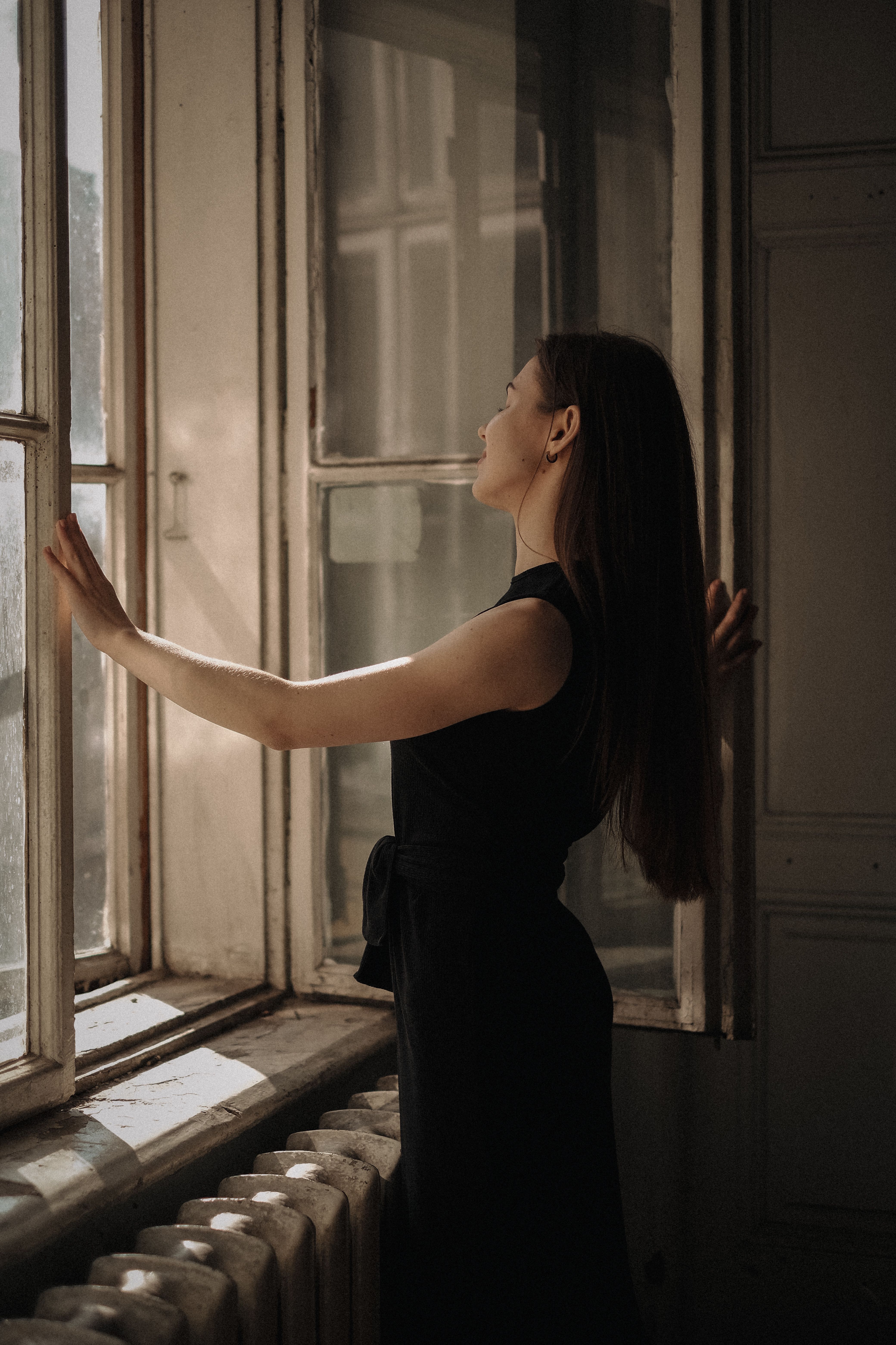 Woman in a Black Dress Standing in front of a Window · Free Stock Photo
