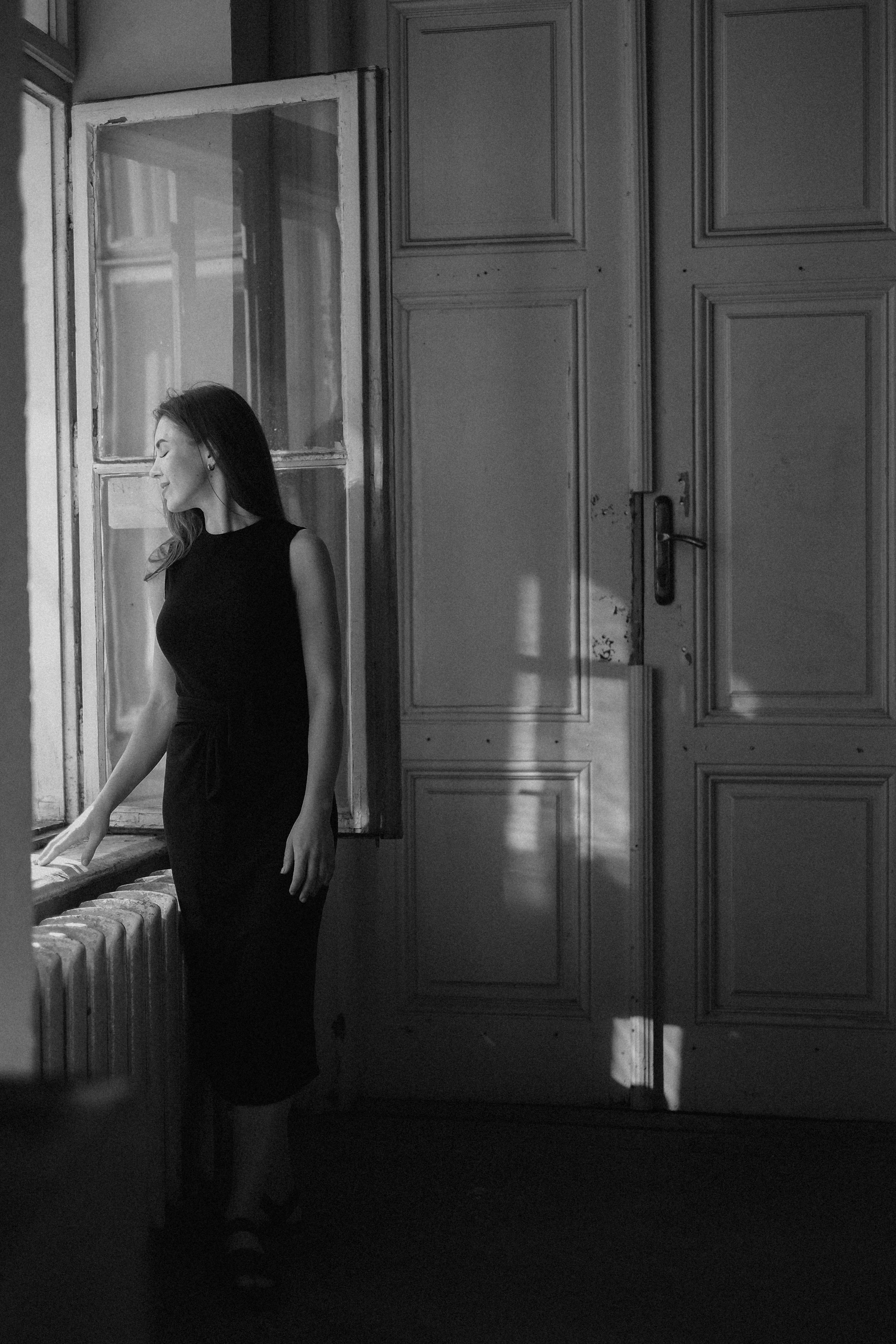 woman in a black dress standing in front of a window