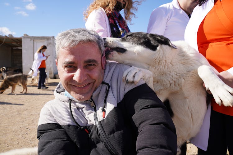 Dog Licking Smiling Man In Jacket