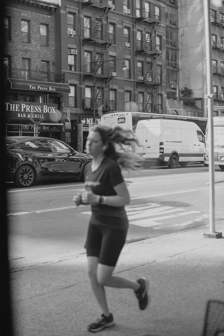 Cars On Street By Runner On Sidewalk In New York City, USA