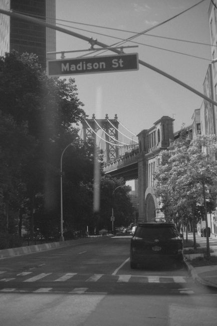 Monochrome image capturing Manhattan Bridge from New York's Madison Street, showcasing urban architecture.