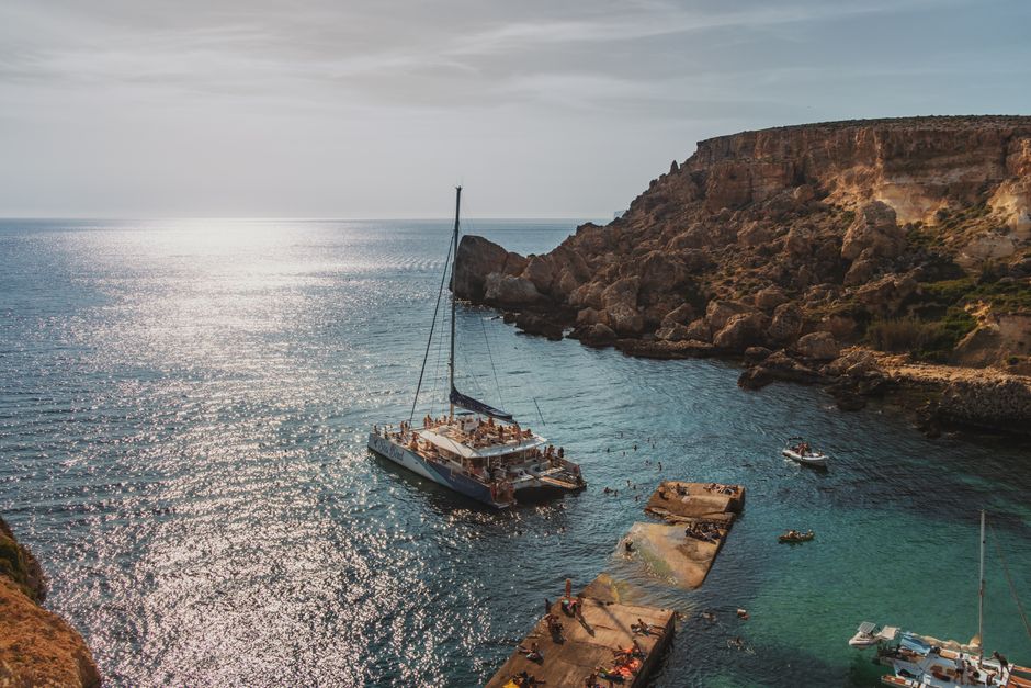Breathtaking Magic Sunset Cruise in Malta Review: An Unforgettable Evening on the Mediterranean Review 2026 - A picturesque coastal bay with yachts and swimmers under a warm sun against dramatic cliffs.