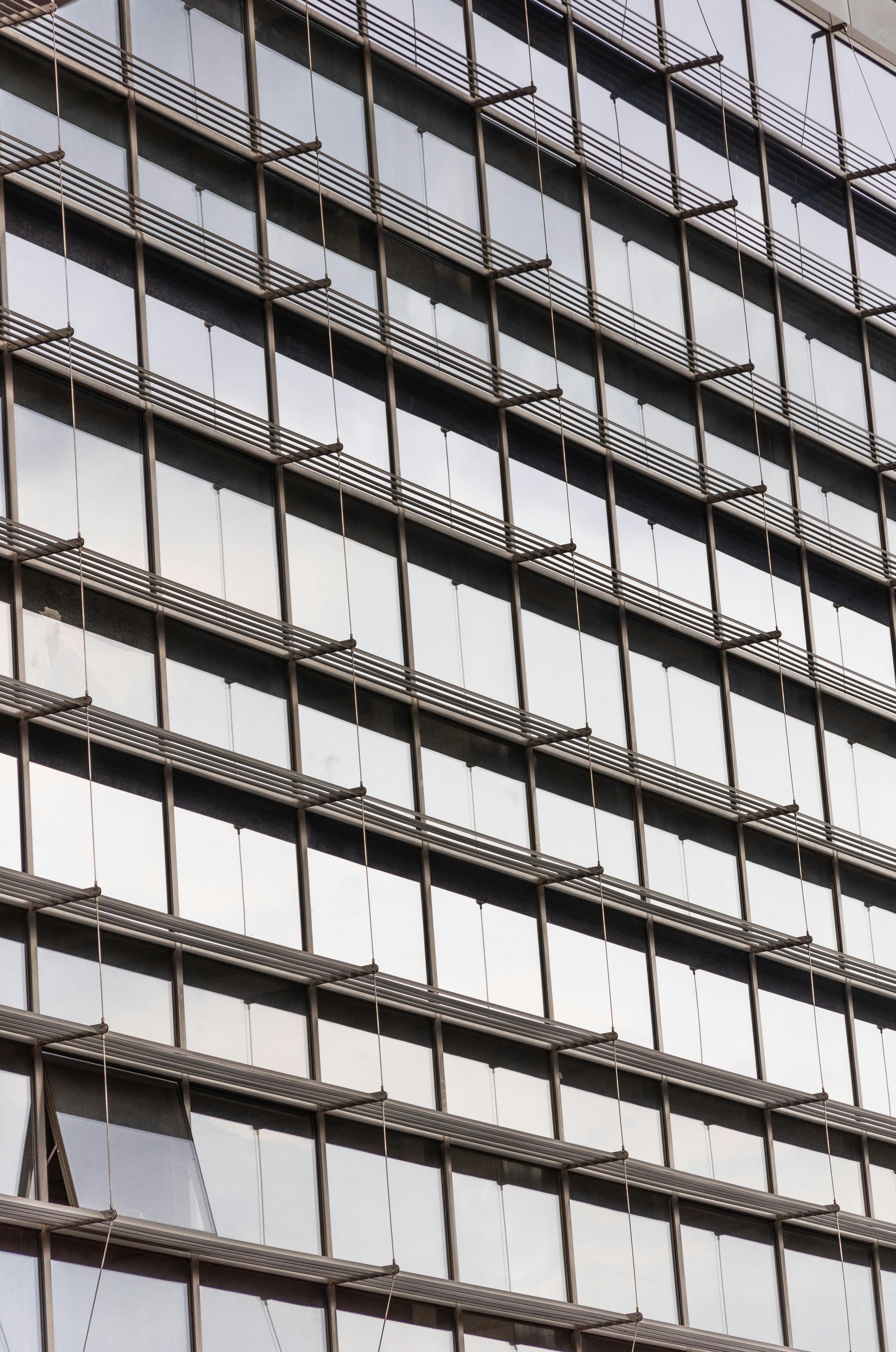 Close-up of a modern office building facade with reflective glass windows creating an urban pattern.