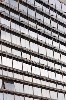 Close-up of a modern office building facade with reflective glass windows creating an urban pattern.