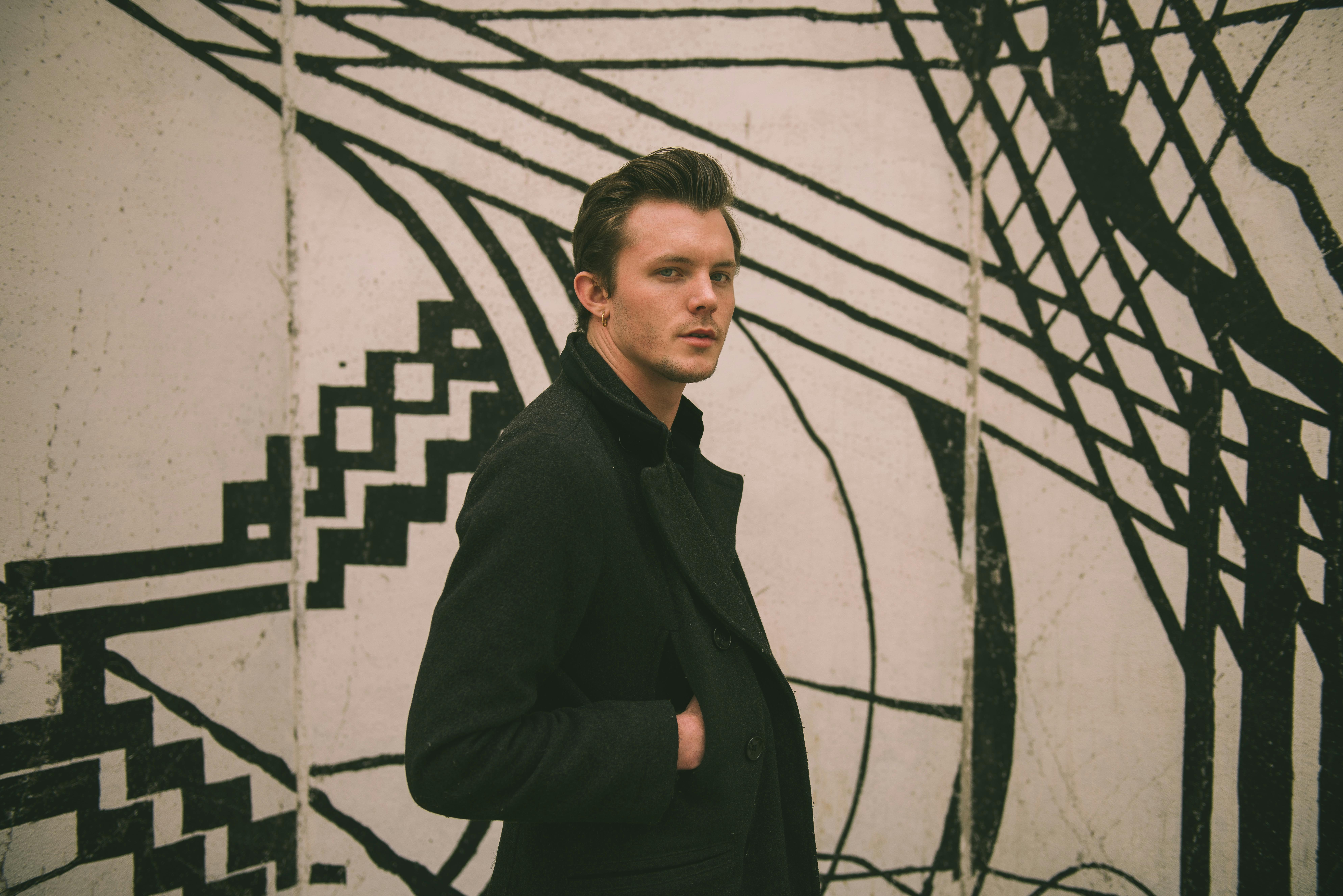 时尚男模特在户外独特的黑白壁画旁摆姿势