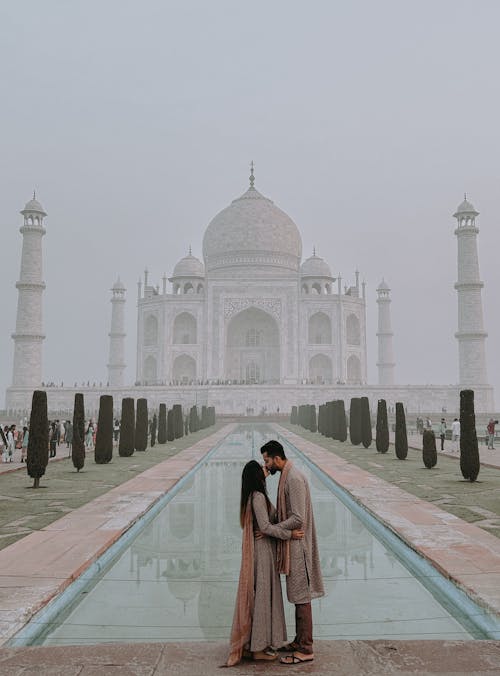 Woman and Man Kissing in front of Taj Mahal in a Foggy Morning