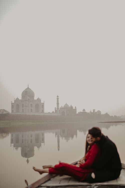Free A couple embraces on a boat with a serene view of the Taj Mahal in the background. Stock Photo