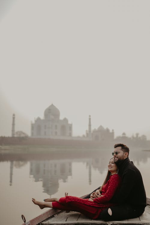 Couple Sitting by the Water with a View of the Taj Mahal, India 