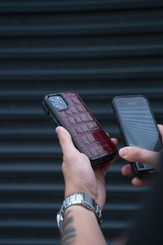 A person holds two smartphones with unique cases, demonstrating a comparison.