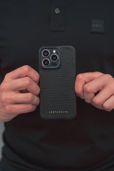 Close-up of a man holding a smartphone with a stylish black case, showcasing tech elegance.